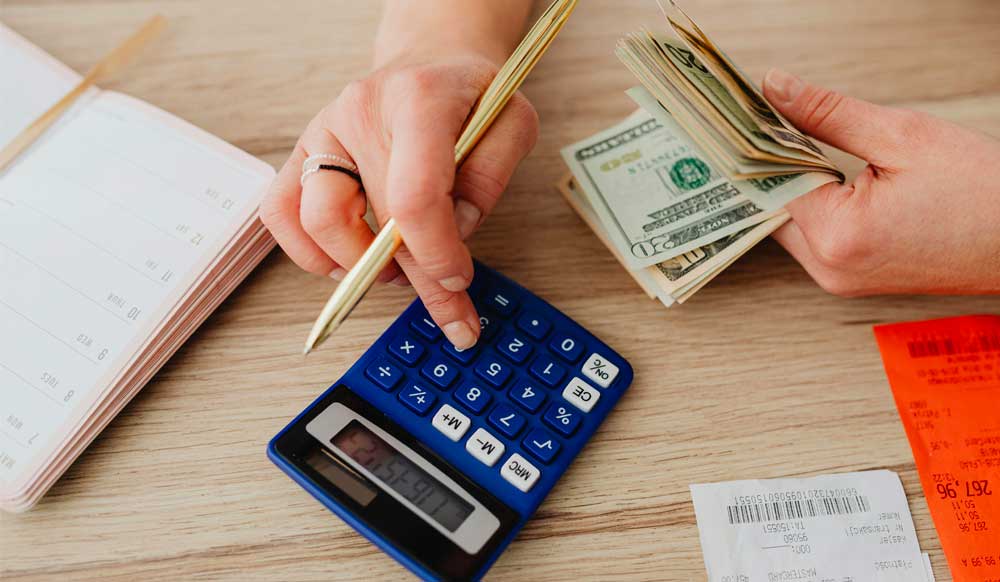 person calculating cost with cash in hand